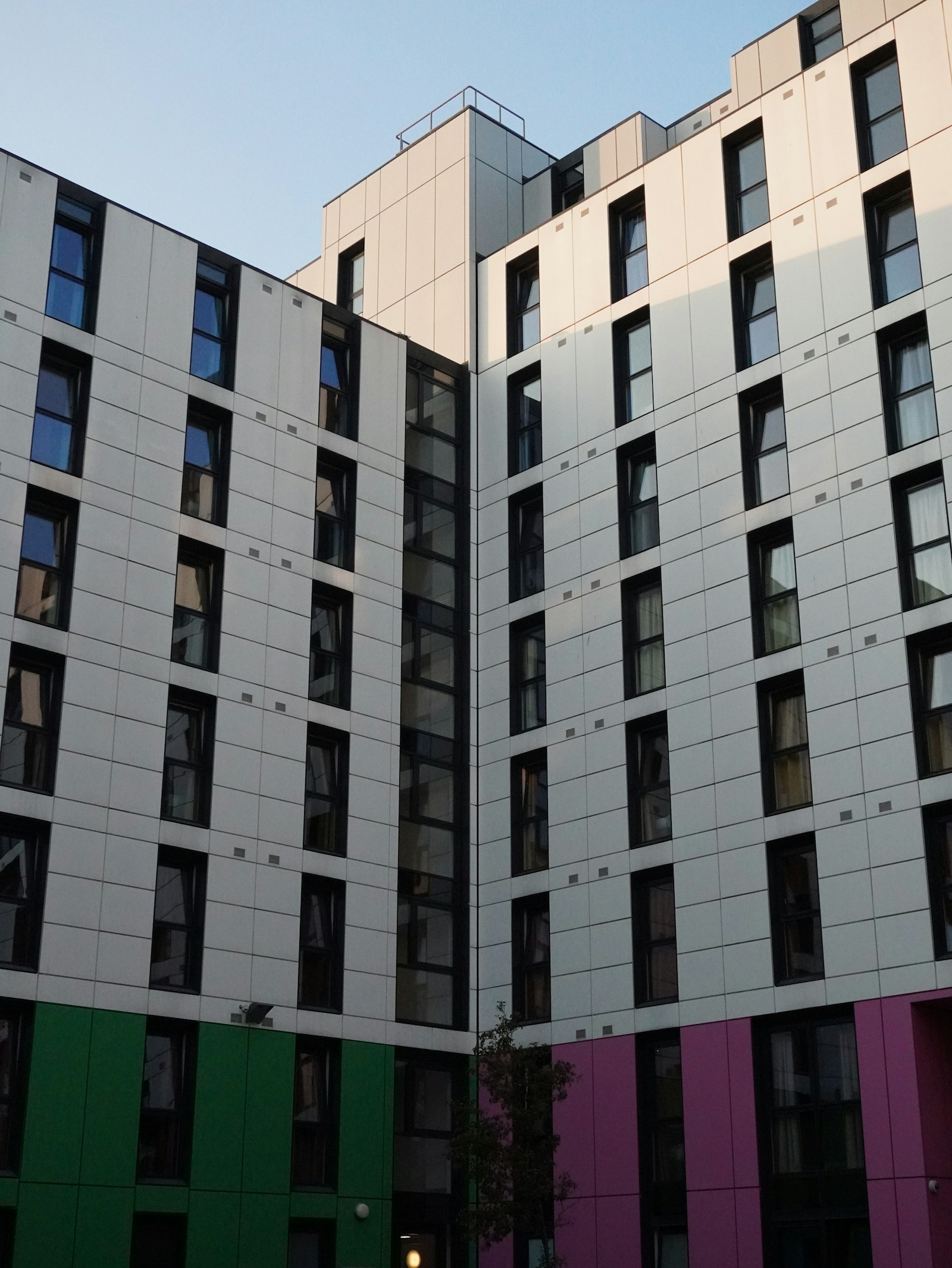 Modern student accommodation building with white, green and pink facade panels